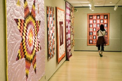 A visitor to Squires Perspectives Gallery looks at the quilts and other fabrics on display.
